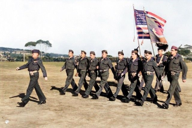 Military personnel marching with American flags at the annual John Basilone parade